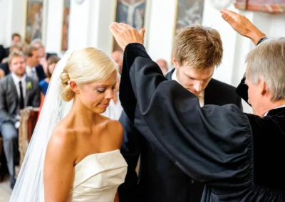 Brautpaar bei kirchlicher Trauung, gesegnet vom Priester in Bernried am Starnberger See. Hochzeitsfotografie.