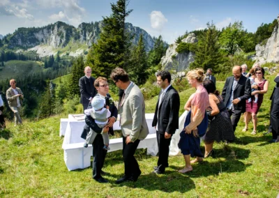 Hochzeit im Freien mit Gaesten bei Kampenwand, Hochzeitsreportage zeigt Menschen vor Bergkulisse