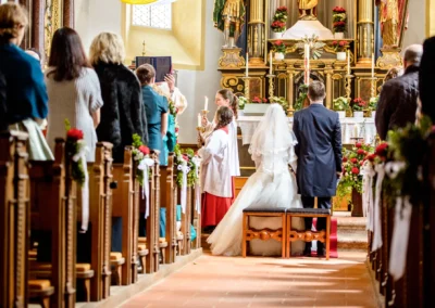 Kirchliche Trauung in Schaftlach: Braut und Bräutigam vor dem Altar, von Familie und Freunden umgeben. Hochzeitsfoto.