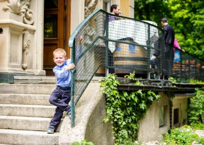 Junge laechelt auf Treppe bei Hochzeit im Luitpoldpark Muenchen, aufgenommen von Hochzeitsfotografen.