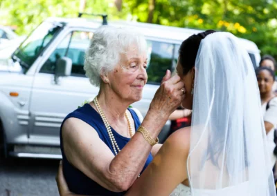 Ältere Frau berührt Braut mit Schleier, emotionale Szene bei Hochzeit in Oberbayern. Hochzeitsreportage zeigt zarte Momente.