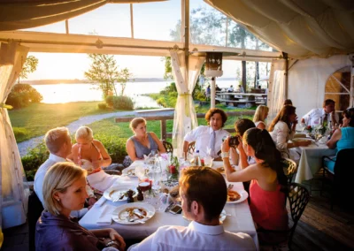 Gäste genießen ein Abendessen bei einer Hochzeitsreportage am Starnberger See, mit Blick auf den Sonnenuntergang.