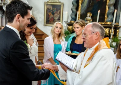 Bräutigam und Braut bei kirchlicher Trauung in Arget. Der Priester hält eine Zeremonie mit Gästen. Hochzeitsfotografie.