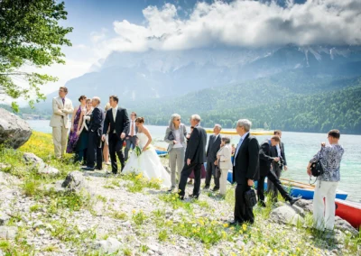 Hochzeitsgesellschaft am Eibseeufer nahe Garmisch, aufgenommen bei einer Hochzeit. Berge im Hintergrund.