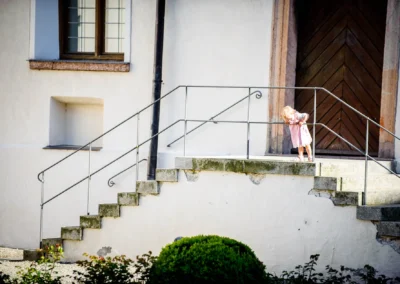 Kleines Kind schaut von Steintreppe bei Hochzeit im Kloster Seeon im Chiemgau. Hochzeitsreportage in Bayern.