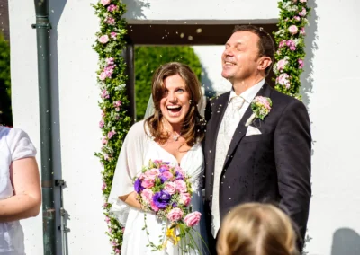 Brautpaar bei kirchlicher Trauung in Sankt Peter, blumenverzierte Kulisse, Hochzeitsszene voller Freude in Muenchen.