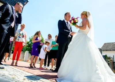 Brautpaar tauscht Ringe bei kirchlicher Trauung in Taufkirchen, umgeben von Gästen. Hochzeitsreportage nahe Muenchen.