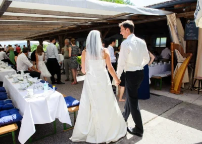 Brautpaar bei Hochzeitsfeier auf Sprengenöder Alm nahe Starnberger See, Gäste im Hintergrund, festliche Atmosphäre. Hochzeitsfoto in Oberbayern.
