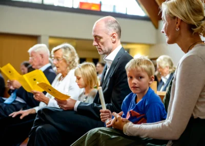 Familie waehrend kirchlicher Trauung in Feldafing am Starnberger See; Kind mit Kerze, Hochzeitsfotografie.