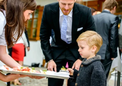 Kind bei einer Hochzeit nahe Tegernsee bekommt Essen serviert. Hochzeitsfotografie zeigt lebendige Momente.