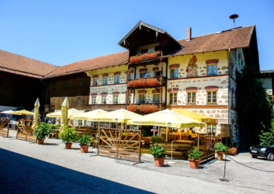 Landgasthof mit blumengeschmücktem Balkon und gelben Sonnenschirmen, Hochzeitsreportage nahe Rosenheim.