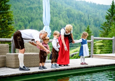 Großeltern mit Kindern in Tracht beim Teich in Almbad-sillberghaus bei Hochzeit. Hochzeitsreportage in Oberbayern.
