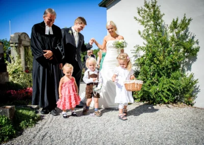 Brautpaar mit Kindern und Pastor vor Kirche in Bernried, Hochzeitsfoto bei sonnigem Wetter, Hochzeitsfotograf.