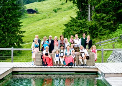 Gruppe von Hochzeitsgaesten in traditioneller Tracht vor gruener Landschaft am Sillberghaus in Oberbayern.