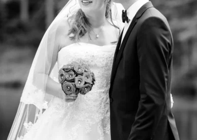 Brautpaarfoto bei der Hochzeit in Grainau am Badersee. Braut mit Blumenstrauss und Bräutigam im Anzug lächeln.