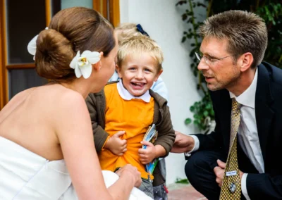Braut, Kind und Mann lachen bei Hochzeit auf Gut Thurnsberg, Hochzeitsfotografie in Oberbayern.