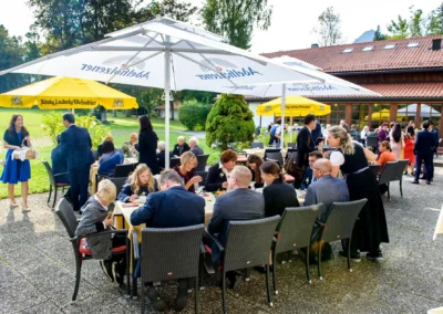 Hochzeitsreportage im Aurachhof: Gäste unter Sonnenschirmen geniessen Feierlichkeit im Freien.