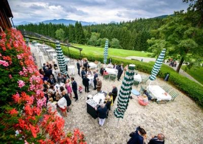 Hochzeitsgesellschaft im Freien bei Margarethenhof, bunte Blumen entlang der Terrasse mit Blick auf die Berge.
