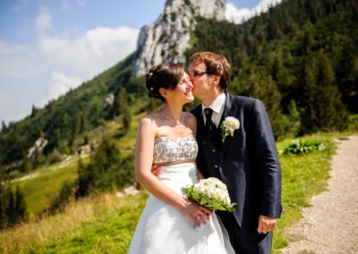 Brautpaar posiert vor malerischer Bergkulisse bei der Hochzeit in der Naehe von Aschau im Chiemgau, Hochzeitsfoto.