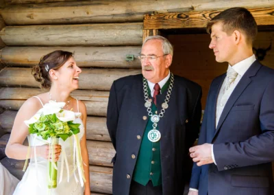 Brautpaar lacht mit Trauzeugen im Freien bei der Hochzeitsreportage am Eibsee. Fröhliche Momente bei der Hochzeit.