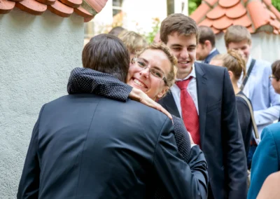 Gaste umarmen sich freudig auf einer Hochzeit in Schwabing, fotografiert vom Hochzeitsfotografen aus Muenchen.