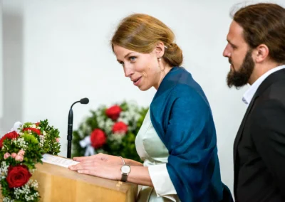 Frau haelt Rede bei kirchlicher Trauung in Schaftlach, dekorierte Kanzel, Hochzeitsreportage, Hochzeitsfotograf.