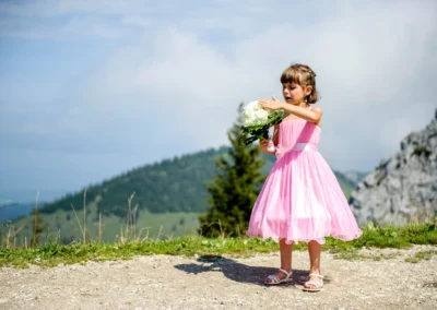 Mädchen im rosa Kleid mit Blumenstrauss bei Hochzeit nahe Kampenwand in Oberbayern fotografiert. Hochzeitsreportage.