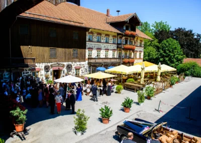Hochzeitsfoto im Landgasthof Stahuber Thal: Gäste unter Sonnenschirmen feiern im Hof bei sonnigem Wetter.