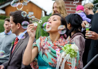Frau pustet Seifenblasen bei Hochzeit in Sauerlach-Arget, eingefangen von Hochzeitsfotograf in lebendiger Momentaufnahme.