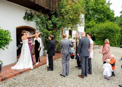 Hochzeitsfoto mit Gaesten und Braut vor einem Gebäude bei Freising, aufgenommen bei einer Hochzeit in Oberbayern.