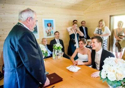 Brautpaar im Standesamt mit Gaesten bei Hochzeitszeremonie, Hochzeitsfotografie nahe Eibsee im Holzraum.