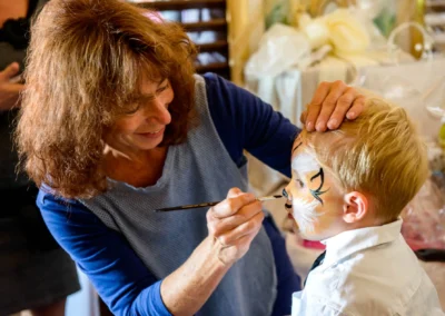 Kinderschminken bei Hochzeit in Karlsfeld. Hochzeitsfotografie dokumentiert Gesichtsbemalung eines Jungen.