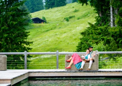 Brautpaar entspannt auf Couch am Steg in Almbad-sillberghaus, umgeben von gruener Landschaft. Hochzeitsfoto in Oberbayern.