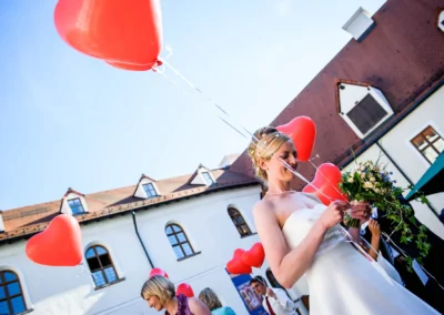 Braut mit Herzballons vor Kloster Seeon bei Hochzeit, Hochzeitsfoto im Chiemgau, emotionale Hochzeitsreportage.