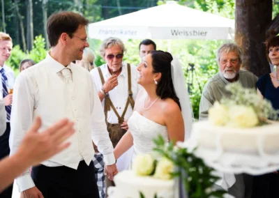 Bräutigam und Braut lächeln bei ihrer Hochzeit in Oberbayern unter freiem Himmel. Hochzeitsfotografie.