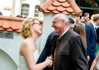 Braut und Gast im Gespraech bei Hochzeit in Muenchen Schwabing vor historischem Gebaeude, aufgenommen vom Hochzeitsfotograf.