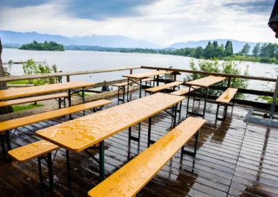 Regennasse Bierbänke auf Terrasse am Staffelsee. Perfekte Kulisse für eine Hochzeitsreportage im Alpenblick.