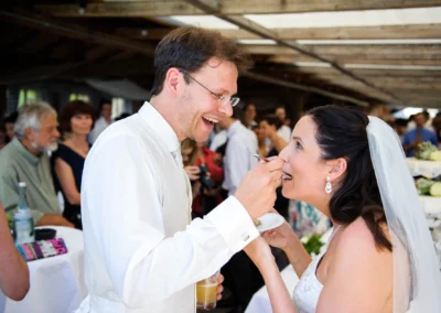 Brautpaar fuettert sich Torte auf Hochzeit in Sprengenoeder Alm bei Muenchen, festgehalten in Hochzeitsfotografie.