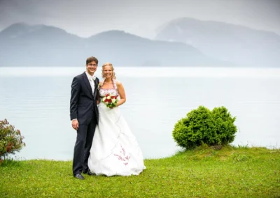 Brautpaar am Walchensee mit Bergkulisse im Hintergrund. Hochzeitsfoto von Hochzeitsfotograf in natuerlicher Umgebung.