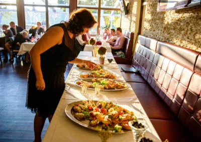 Eine Frau betrachtet Hochzeitsbuffet im Sonnenlicht bei einem Empfang in Karlsfeld, festgehalten in Hochzeitsfotografie.