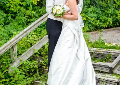 Brautpaar posiert auf Holztreppe mit Blumenstrauss bei Hochzeit in Wolfratshausen, festgehalten von einem Hochzeitsfotograf.