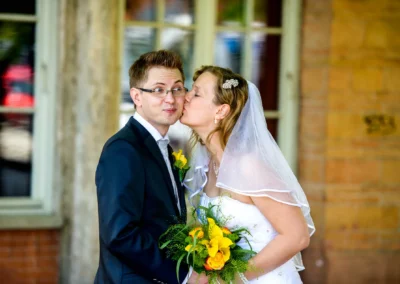 Brautpaar teilt einen Kuss bei Hochzeitsfotosession am Starnberger See, Braut mit Blumenstrauss.