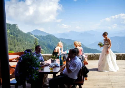 Braut in Hochzeitskleid auf Terrasse mit Blick auf Berge bei einer Hochzeitsreportage in Oberbayern.
