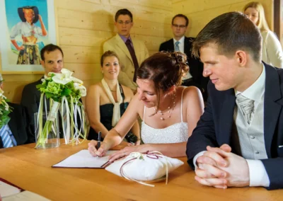 Brautpaar unterzeichnet Dokumente bei Hochzeit nahe Garmisch, Hochzeitsfoto auf Maximiliansinsel Eibsee.