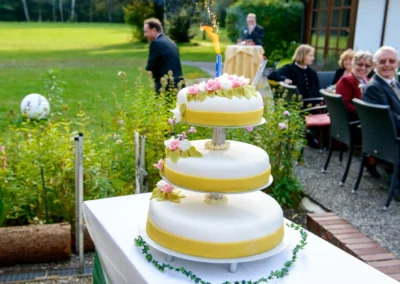 Dreistöckige Hochzeitstorte mit Blumenverzierung im Garten bei Hochzeitsreportage nahe Schliersee.