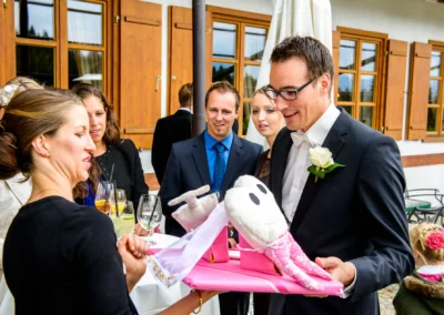 Gespannte Hochzeitsgaeste betrachten ein Geschenk bei einer Hochzeitsfeier im Margarethenhof, nahe Tegernsee.