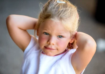 Kleines Maedchen bei Hochzeit nahe Rosenheim, streckt Arme hoch, laechelt in die Kamera. Hochzeitsfotografie in Oberbayern.