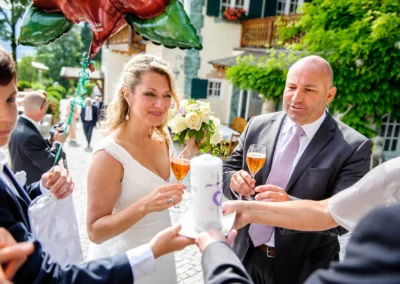 Brautpaar bei Hochzeit im Leeberghof stoesst mit Gaesten an, umgeben von Blumen, festlicher Stimmung und Luftballons.