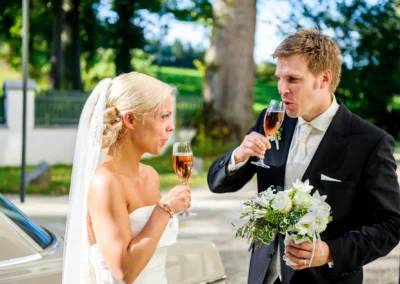 Brautpaar stoßt mit Sekt an bei Hochzeit im Freien, Umgebung von Schlossgut Oberambach, Hochzeitsfotografie.