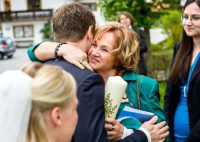 Frau umarmt Mann freudig bei kirchlicher Trauung in Schaftlach, Teil der Hochzeitsfotografie.
